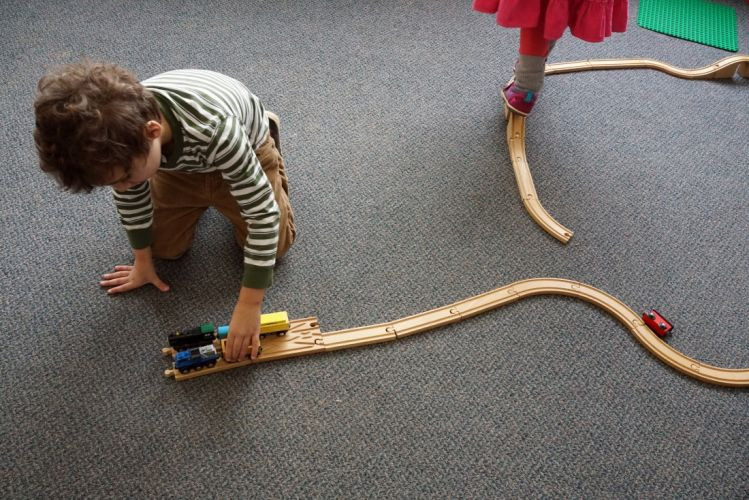Young kid playing with wooden trains
